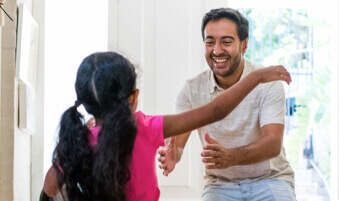 Father hugging daughter in home entryway