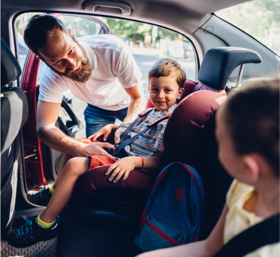 Father buckling young child into a car seat